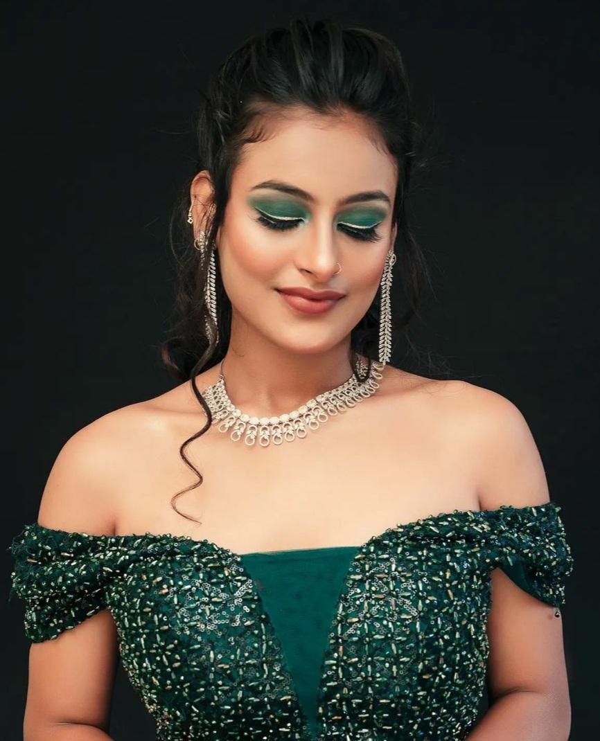 Emerald eyeshadow cocktail makeup with silver jewellery against a black backdrop